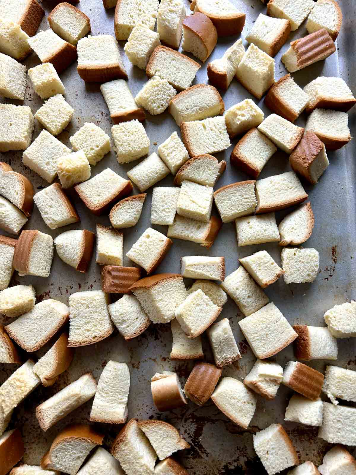 brioche bread cut into cubes on baking pan.