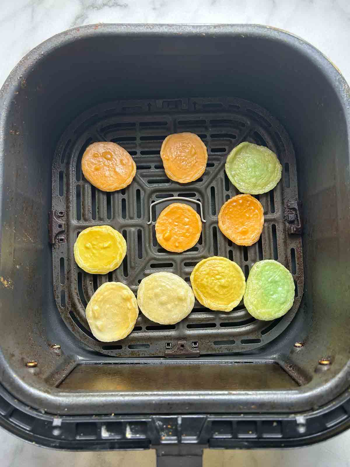 cooked shrimp chips in air fryer basket.