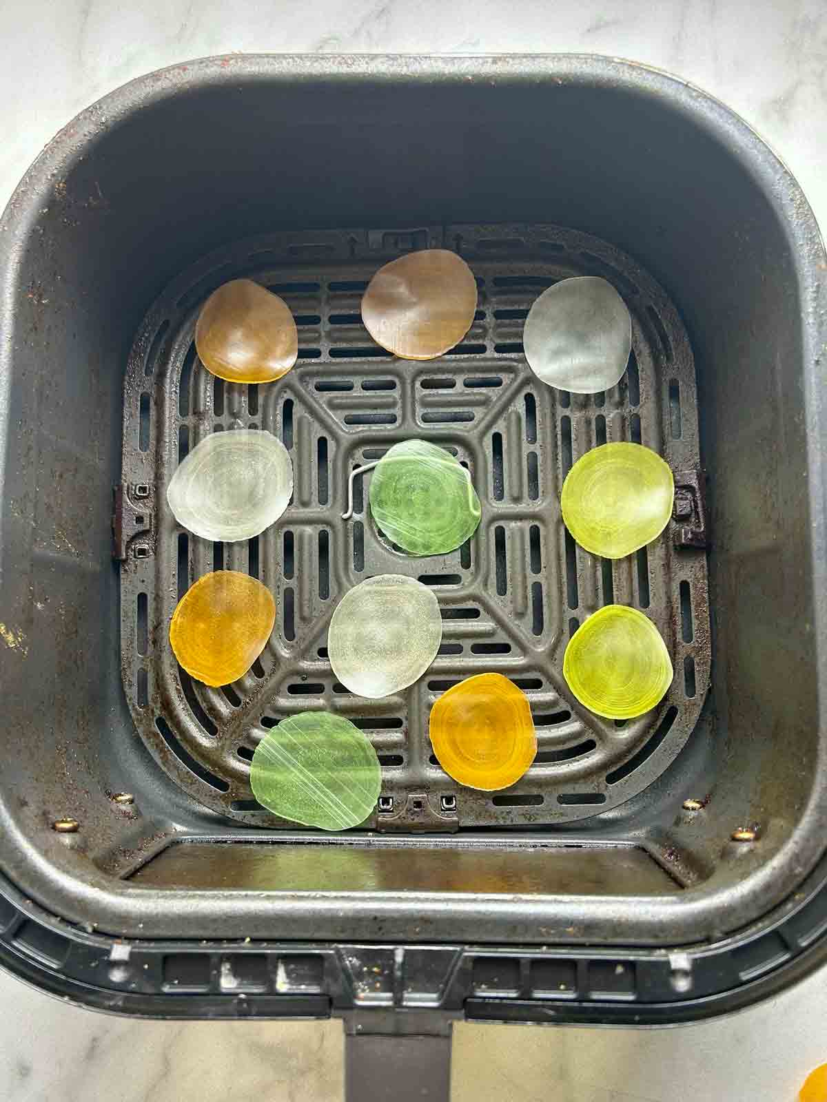 uncooked shrimp chips in air fryer basket.