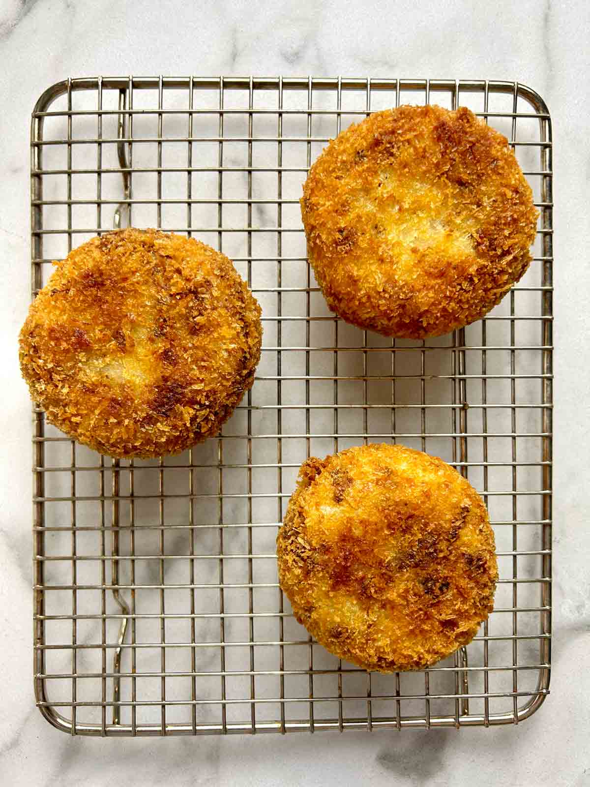 fried croquettes drying on wire rack.