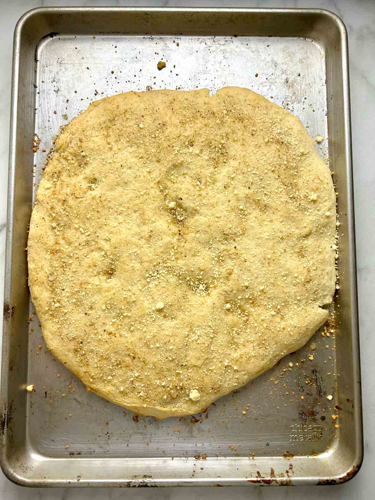 baked dough in pan with parmesan cheese sprinkled on top.