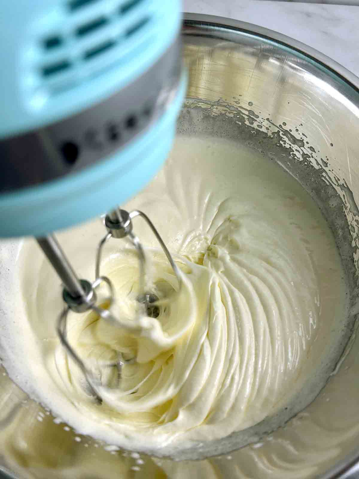 sugar and eggs being beaten until pale and fluffy in bowl.