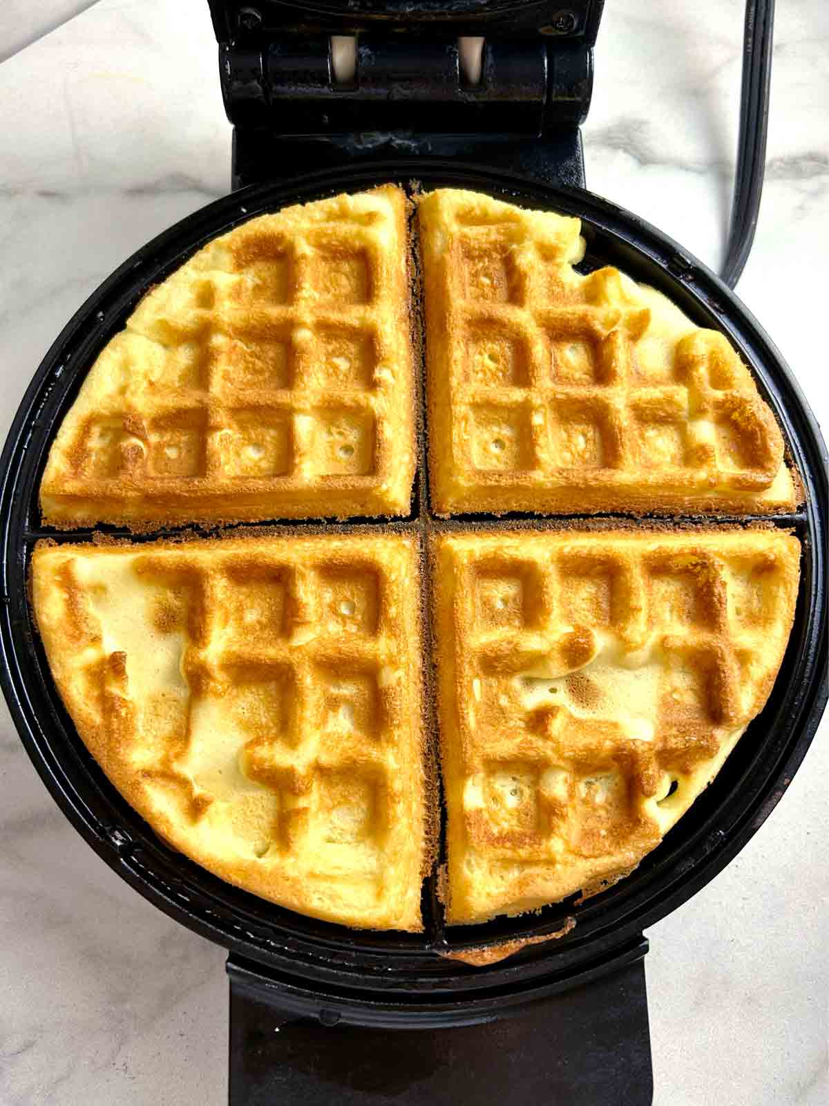 golden brown bubble waffle in waffle iron.