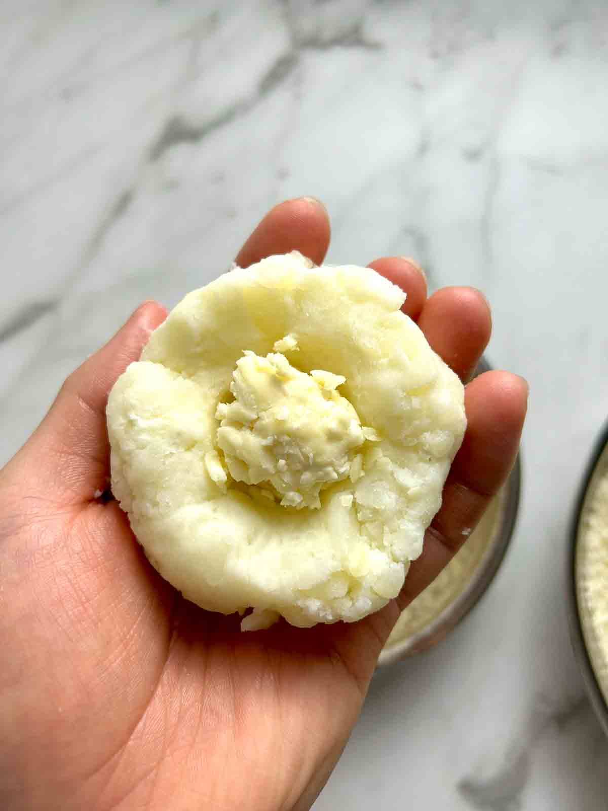 pressing cheese into center of potato ball.