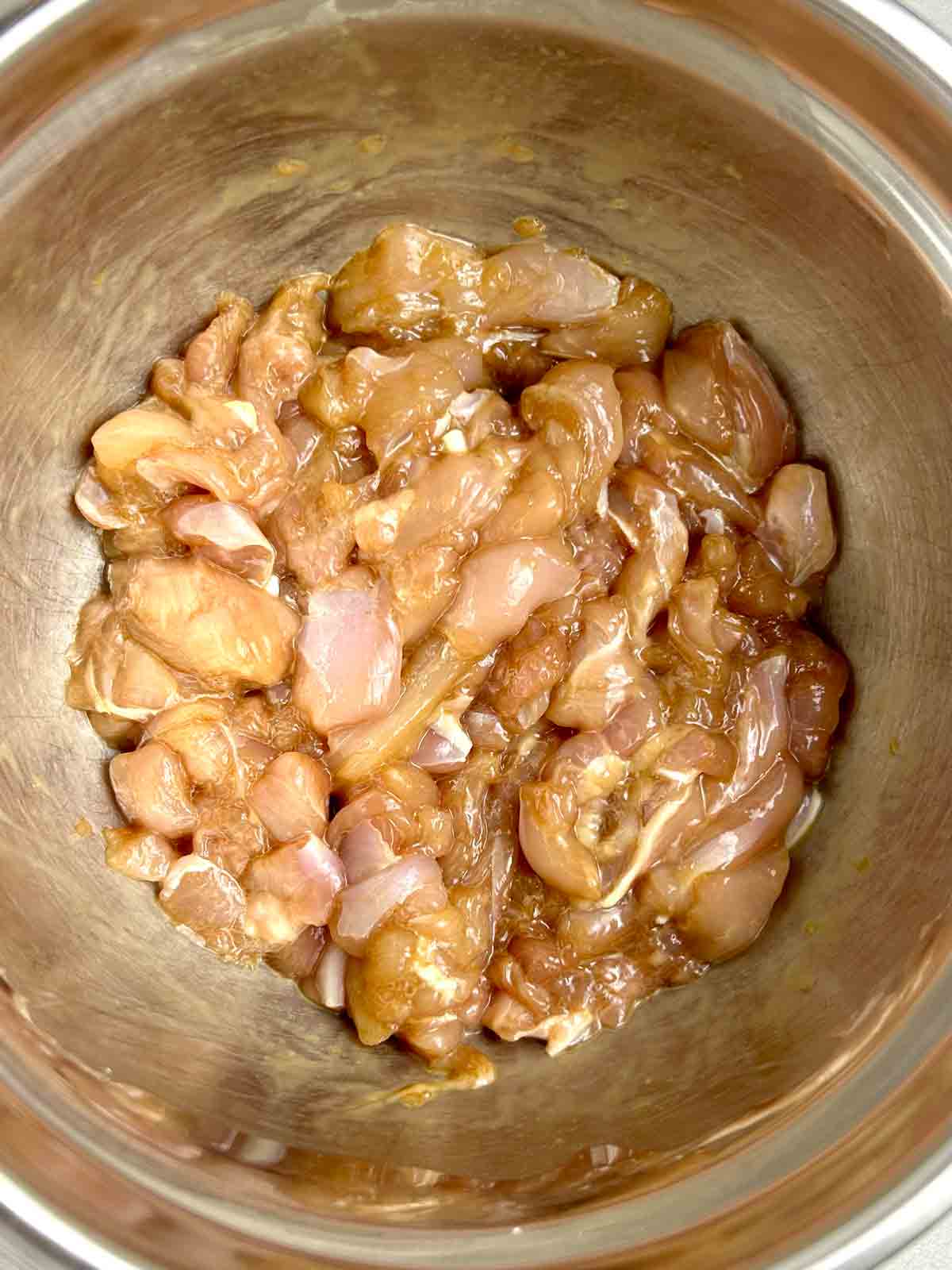 chicken meat being marinated in bowl.