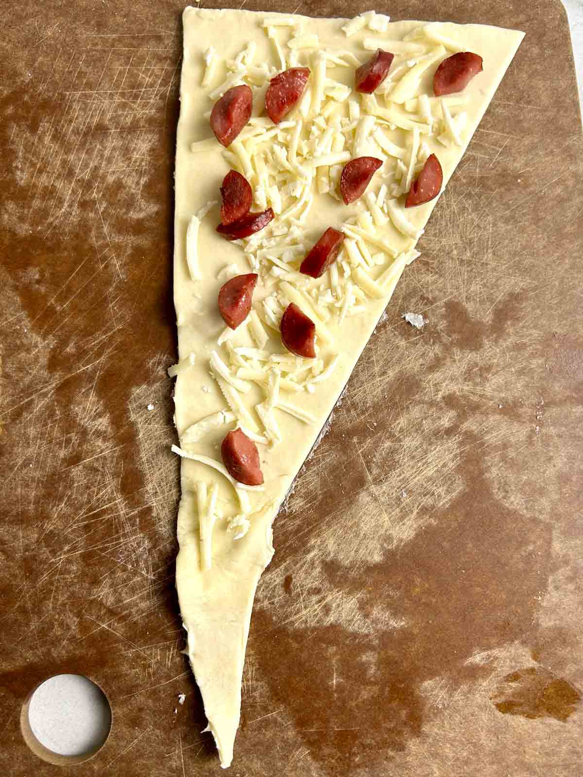 hotdogs and cheese spread on triangle puff pastry.