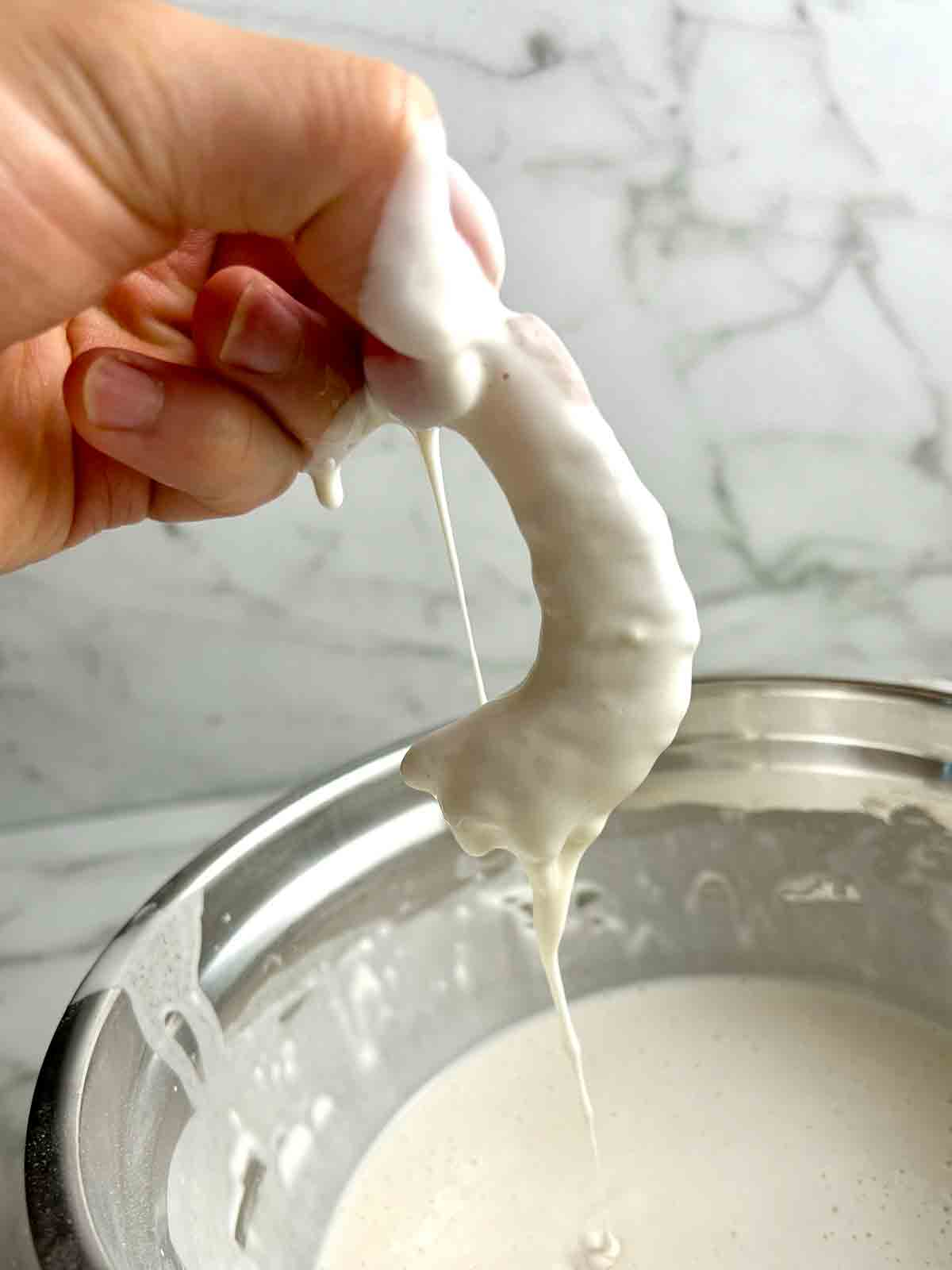 shrimp being lifted out of tempura batter with excess dropping off.