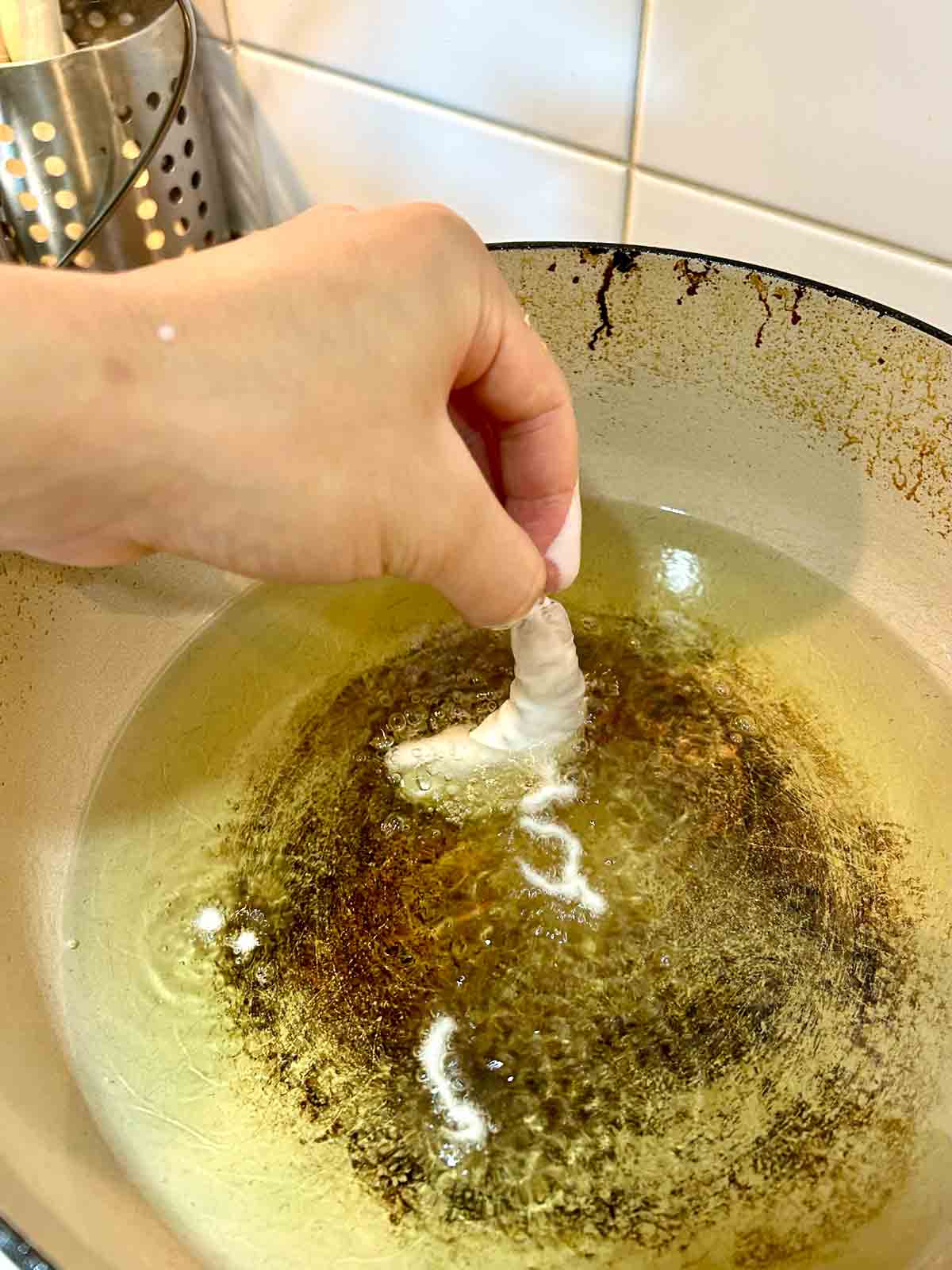 battered shrimp being lowered into hot oil.