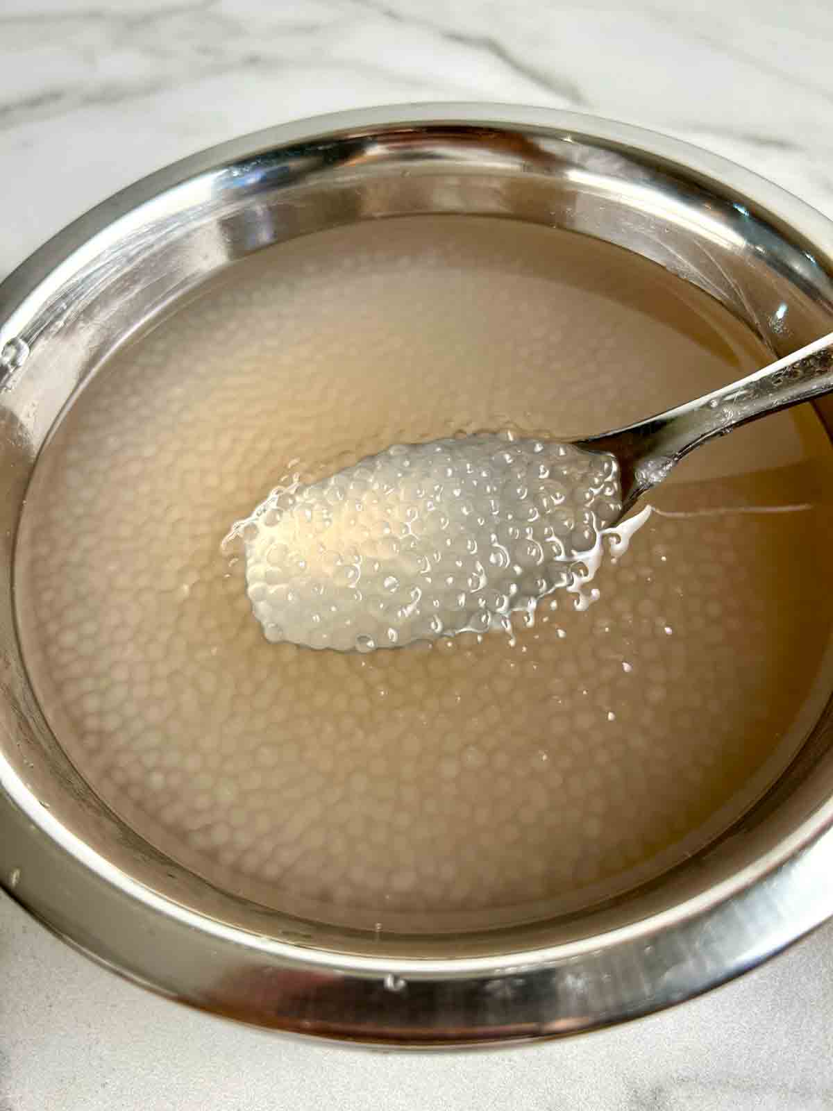 cooked tapioca pearls in bowl of water.