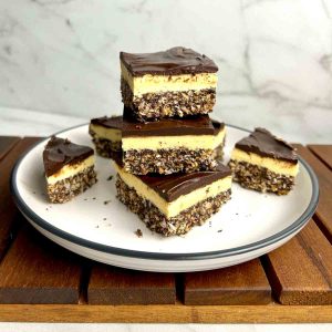 Nanaimo bars stacked on top of each other on plate.