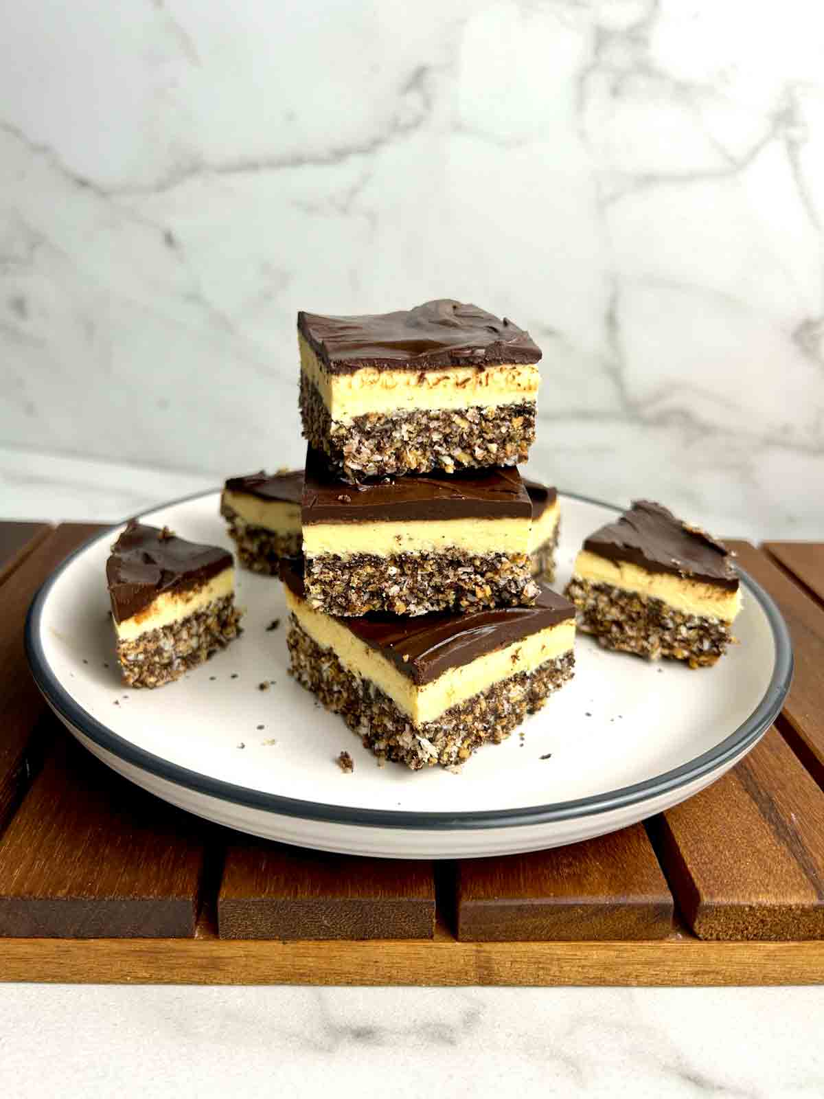 Nanaimo bars stacked on top of each other on plate.