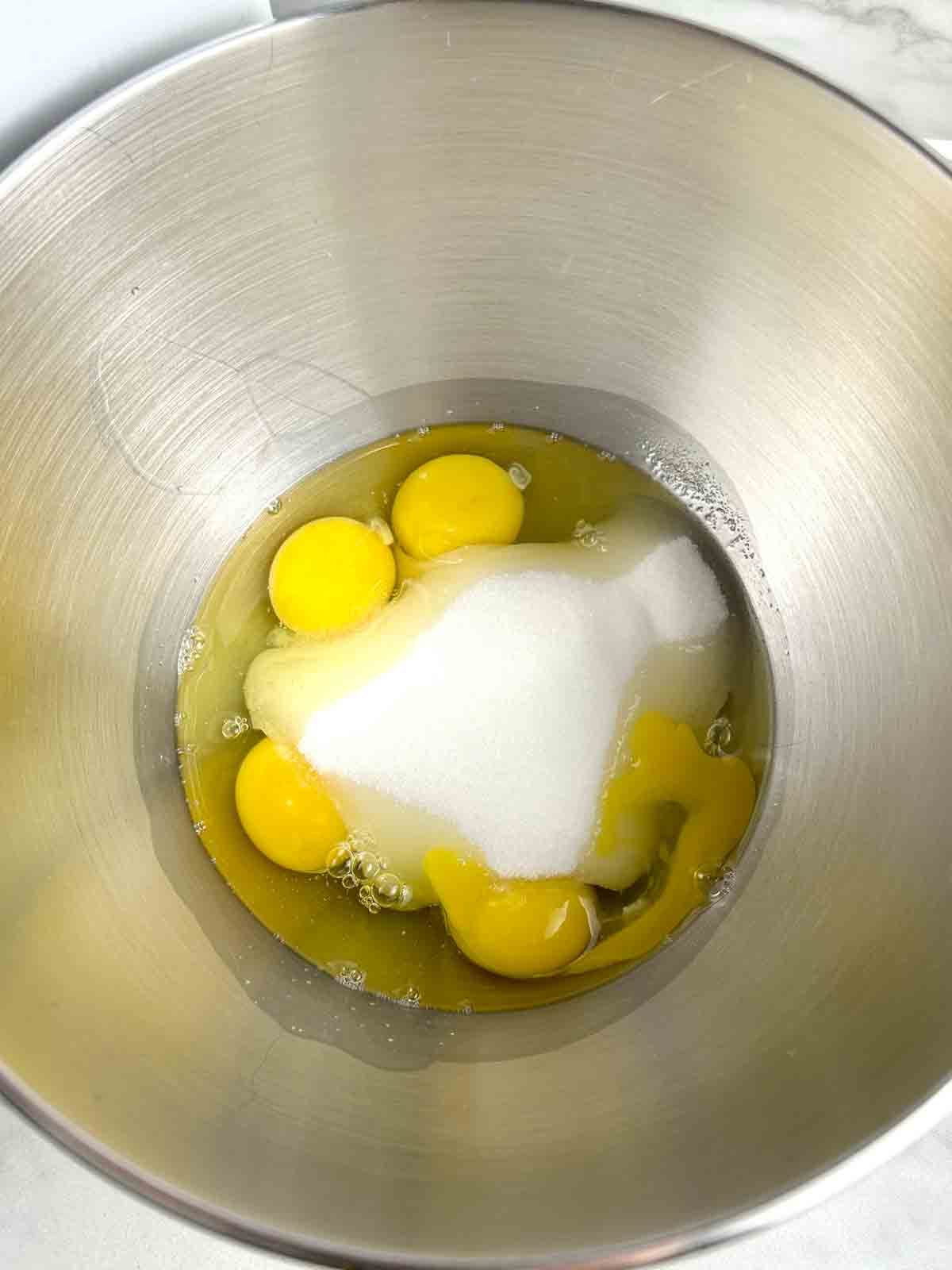 eggs and sugar sitting in stand mixer bowl.