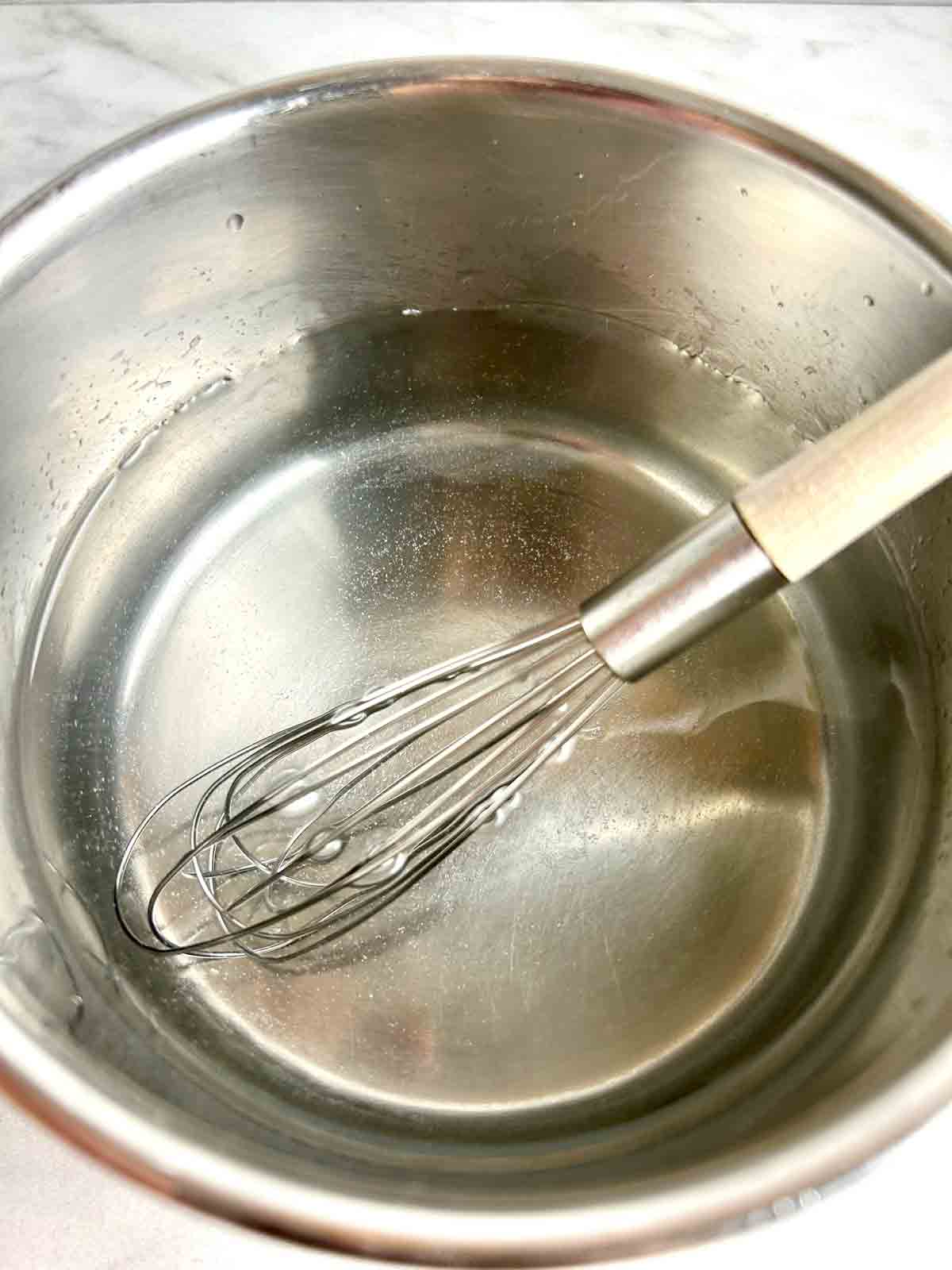 calcium lactate being whisked into pot of water.