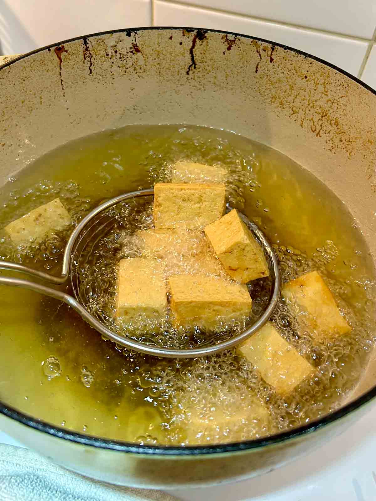 metal spider lifting tofu out of hot oil.