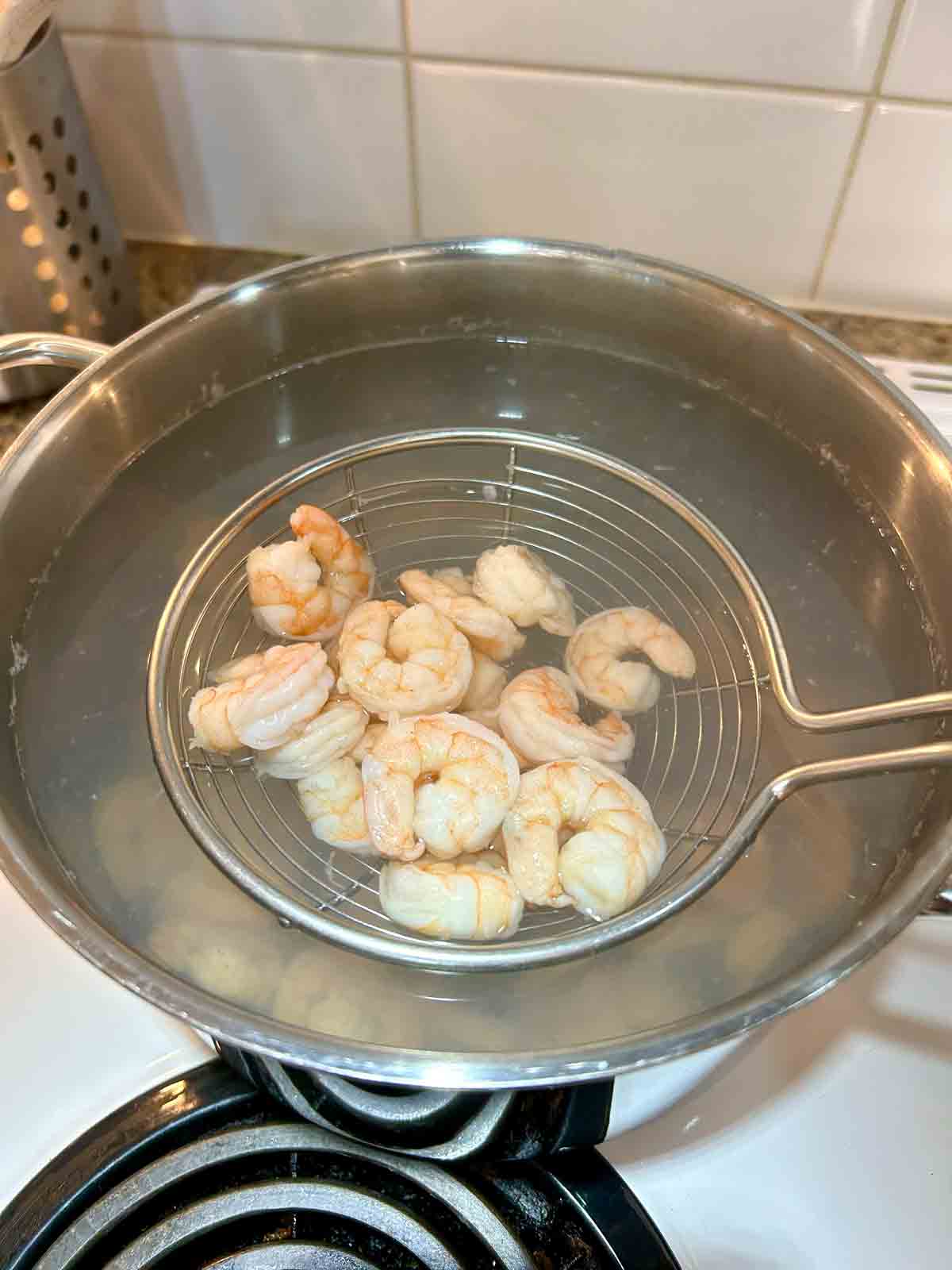 cooked shrimp being lifted out of pot of water.