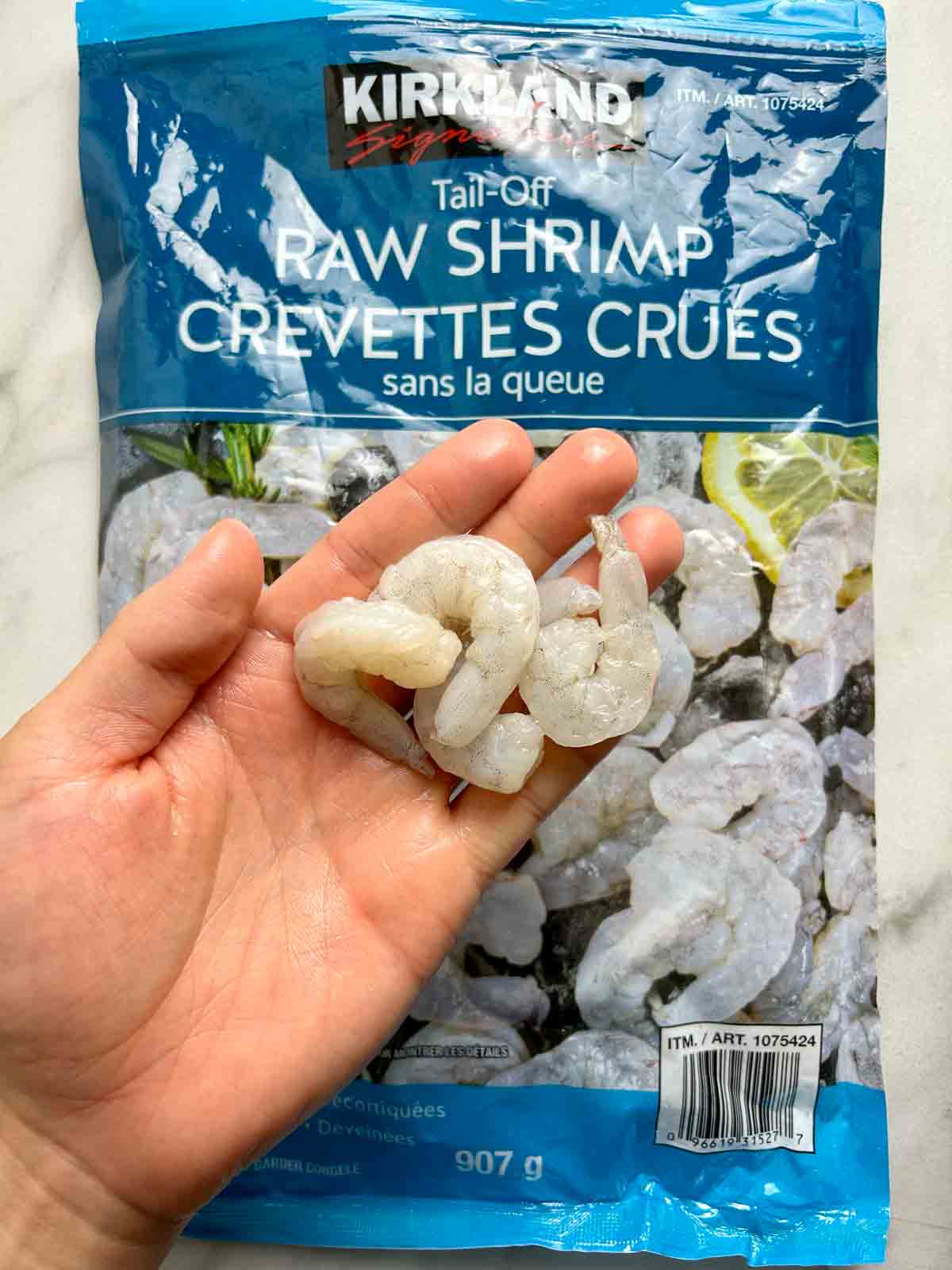 hand holding raw shrimp from Costco shrimp bag.