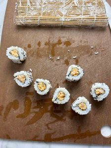 cut pieces of spicy shrimp roll on cutting board.