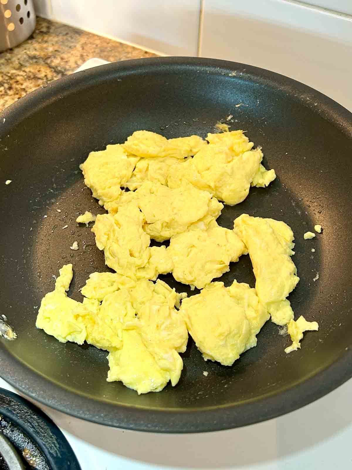 eggs being scrambled in pan.