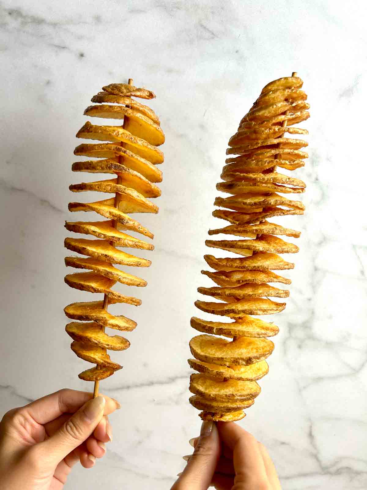 holding two tornado potatoes in air.