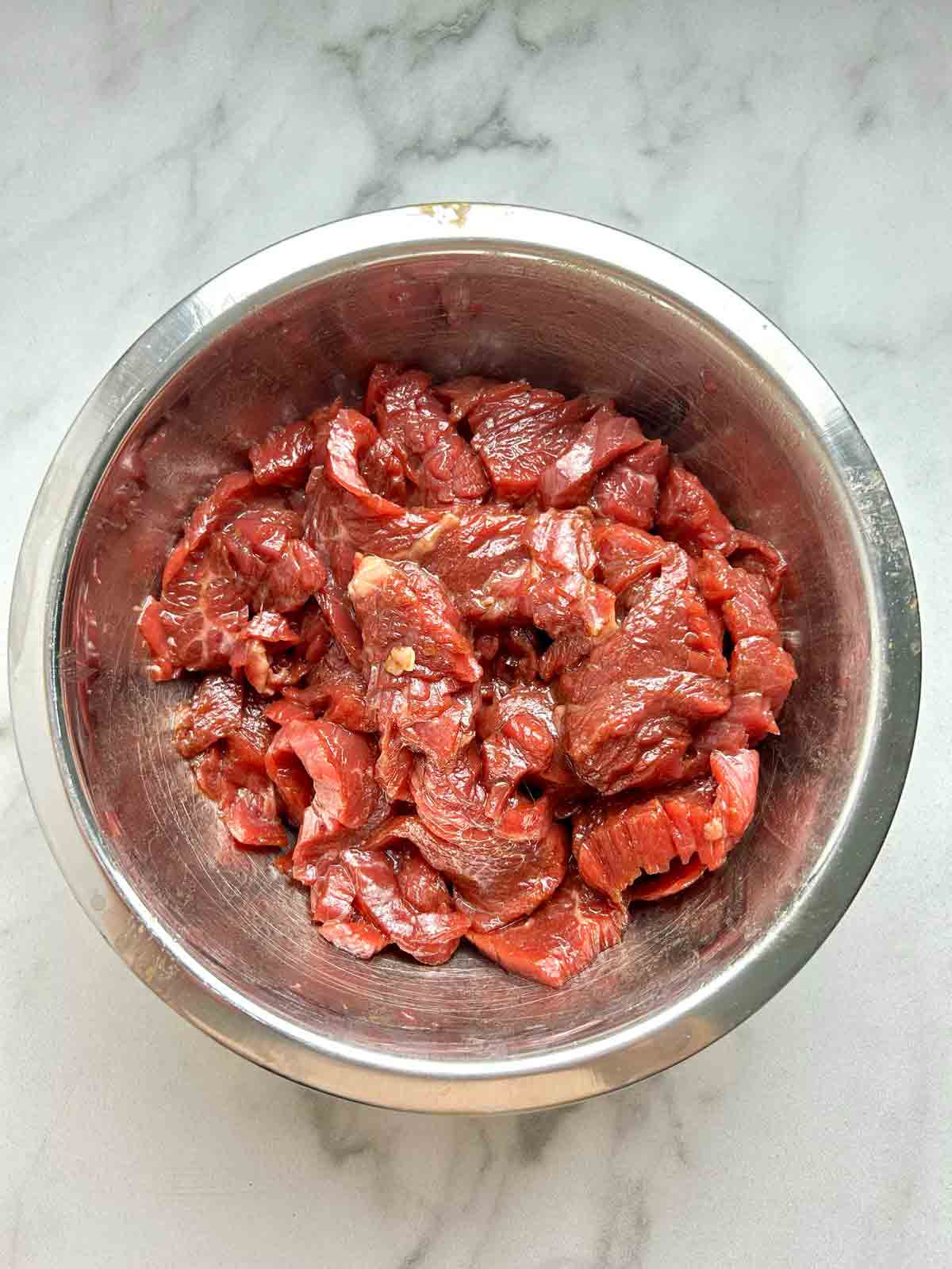 meat being marinated in bowl.