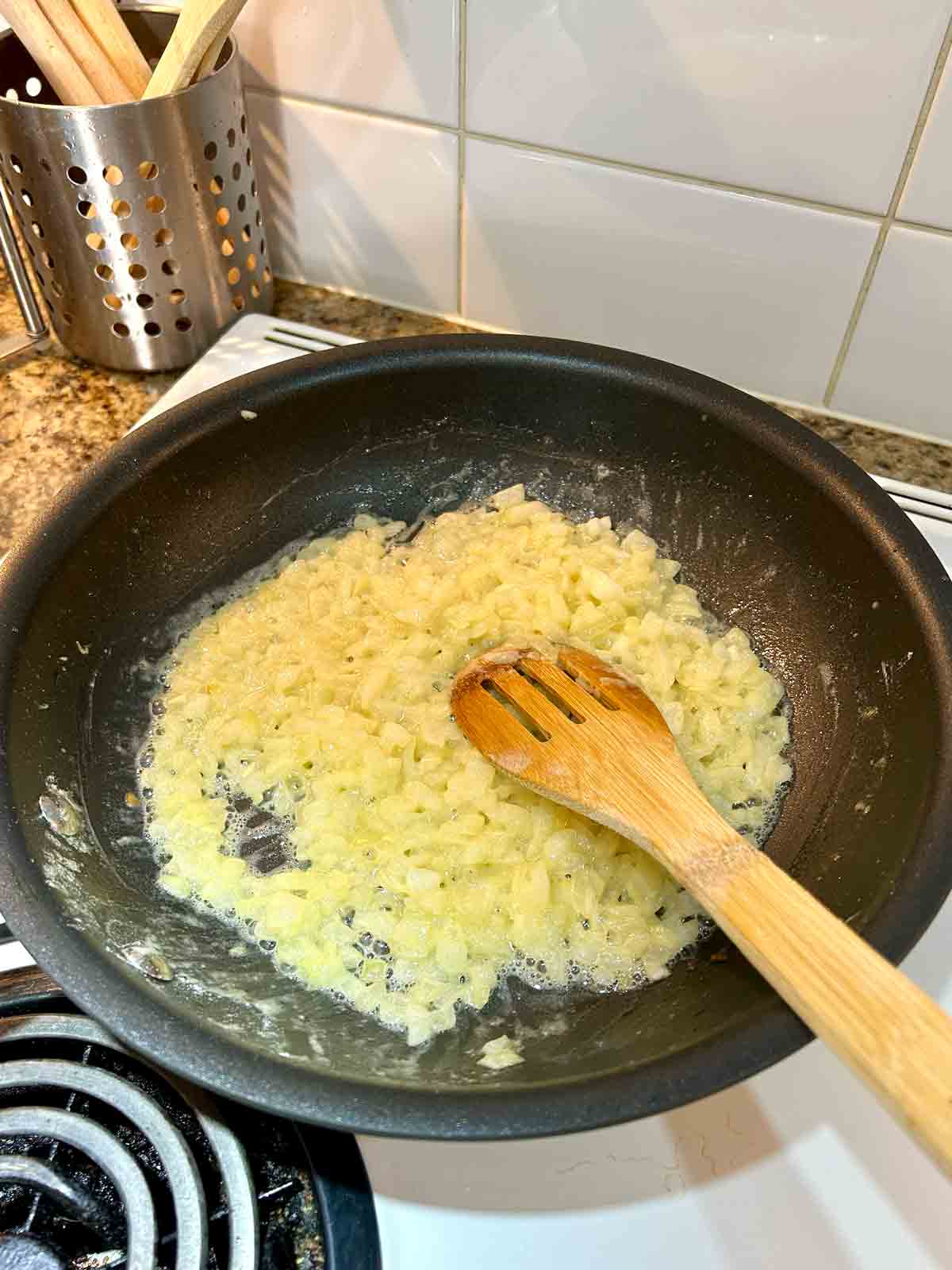 chopped onions being cooked in pan.