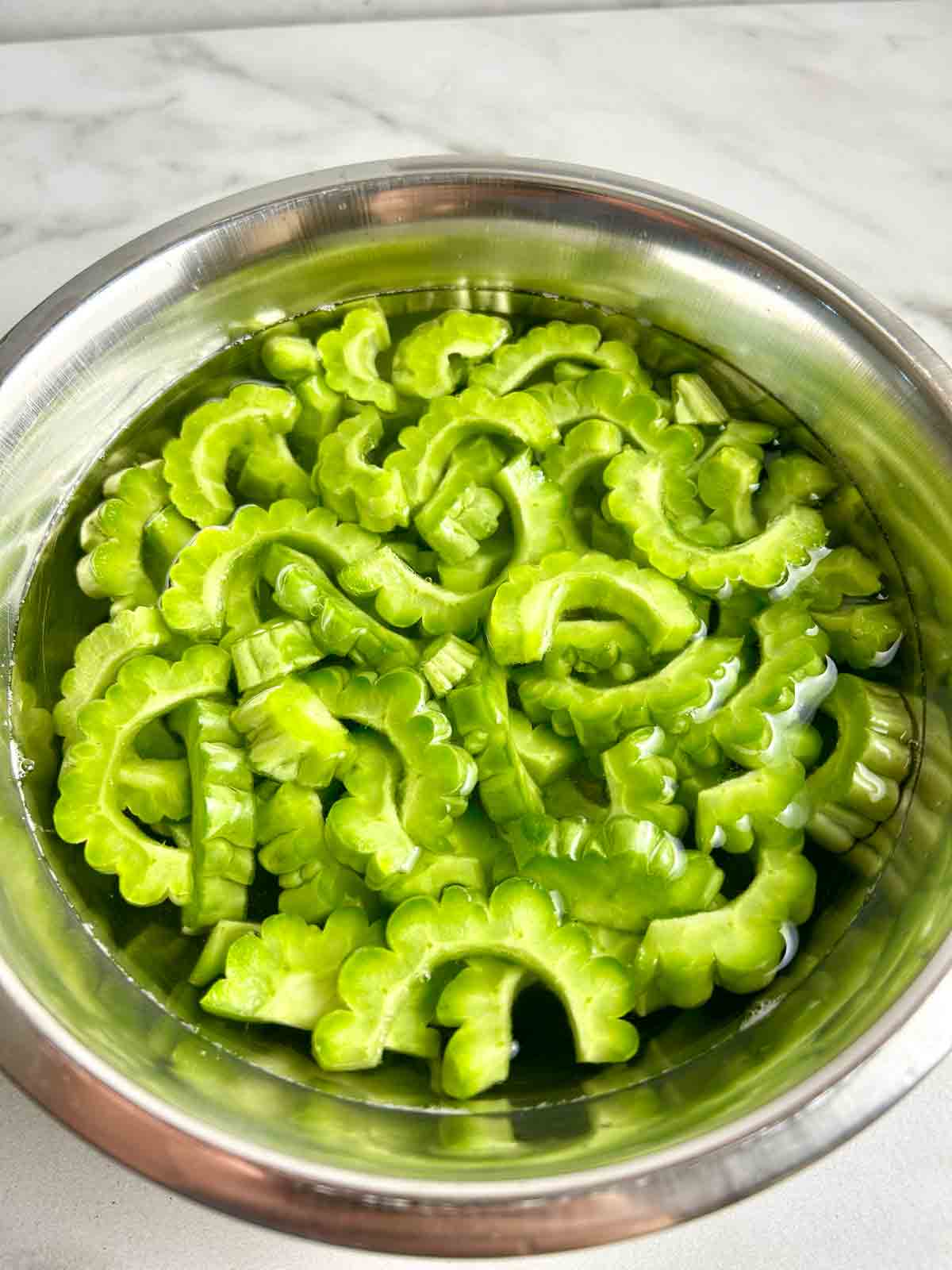 bittermelon slices being soaked in salted water.