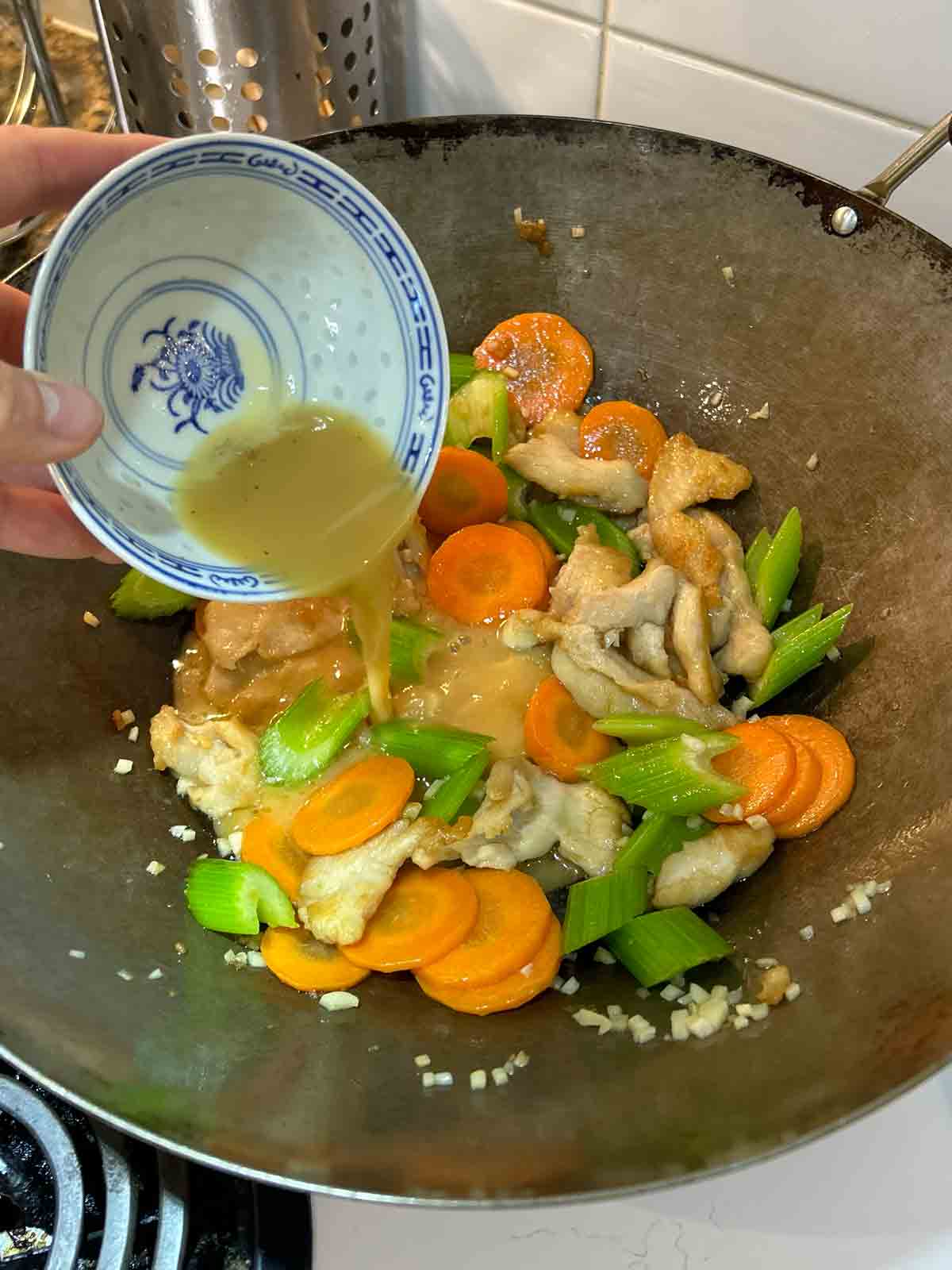 sauce being poured into wok.