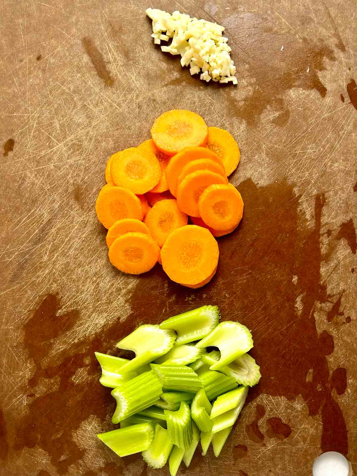 chopped celery, sliced carrots, and chopped garlic on cutting board.