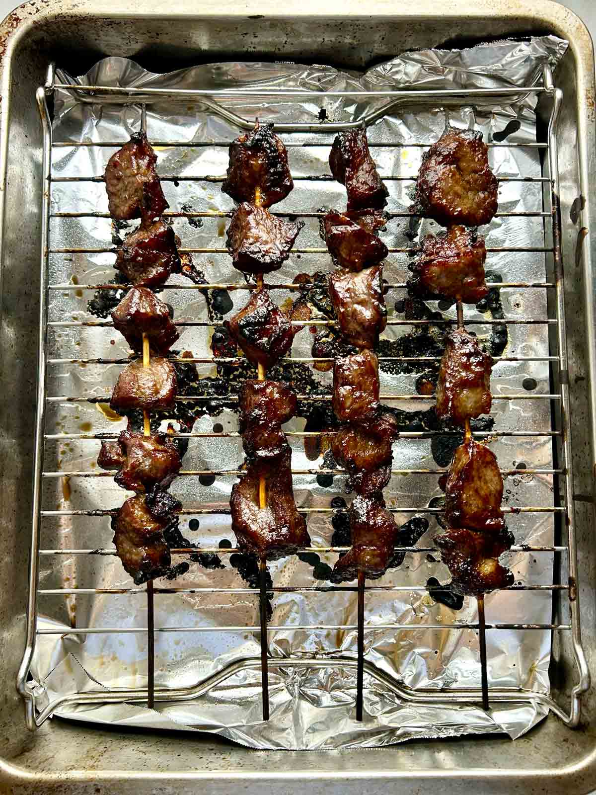 charred beef skewers on roasting rack.