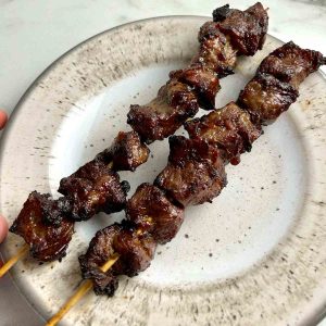 two skewers of beef on a plate.