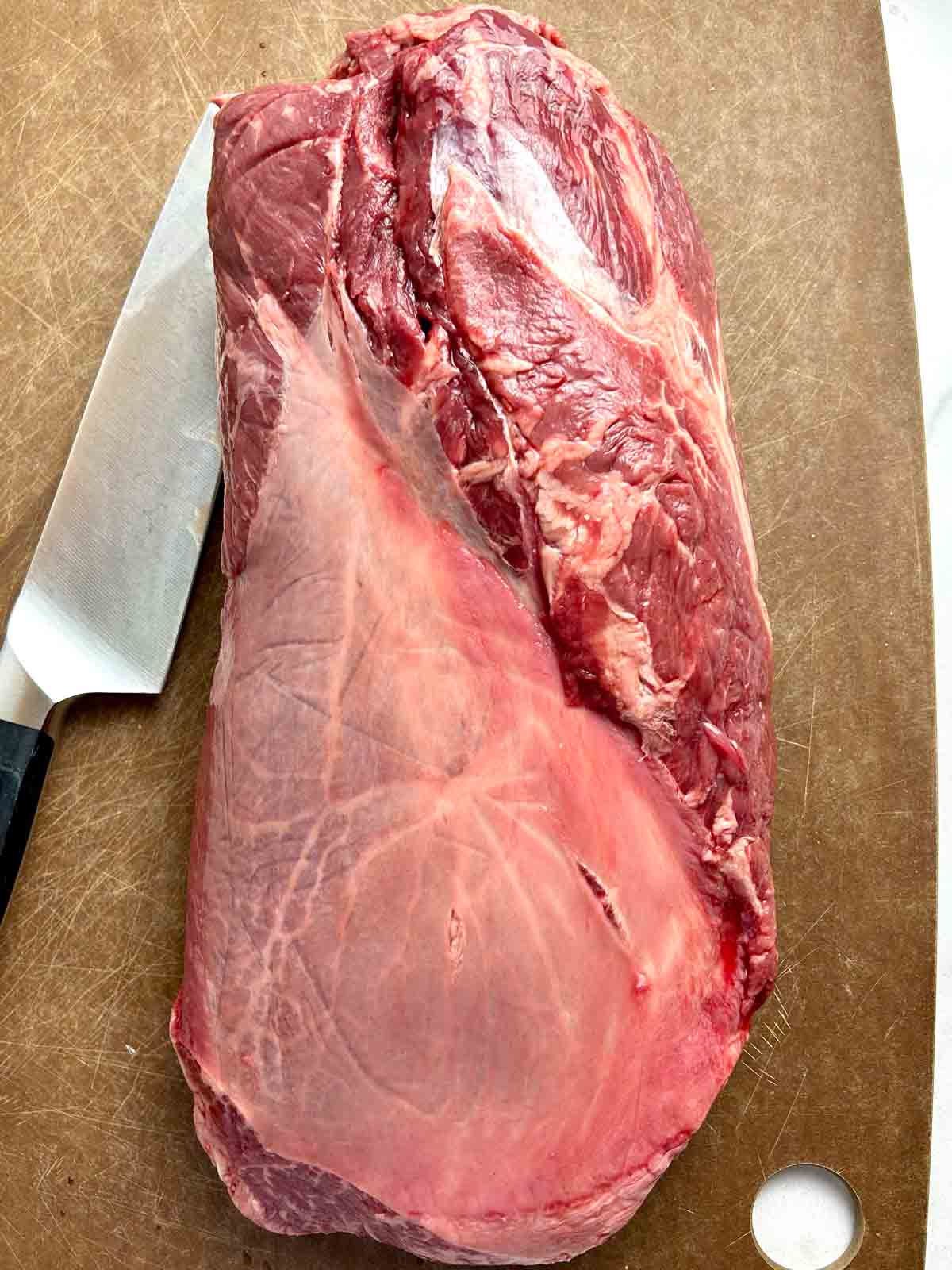 top blade roast on cutting board with knife nearby.