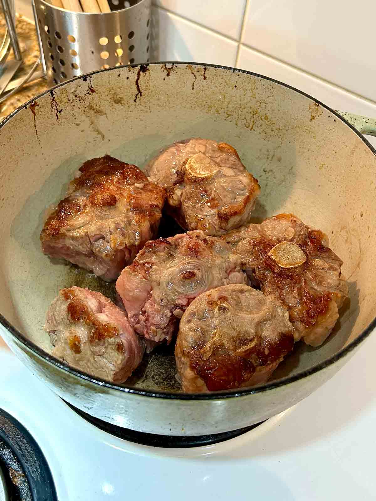 oxtail being seared until brown in Dutch oven.