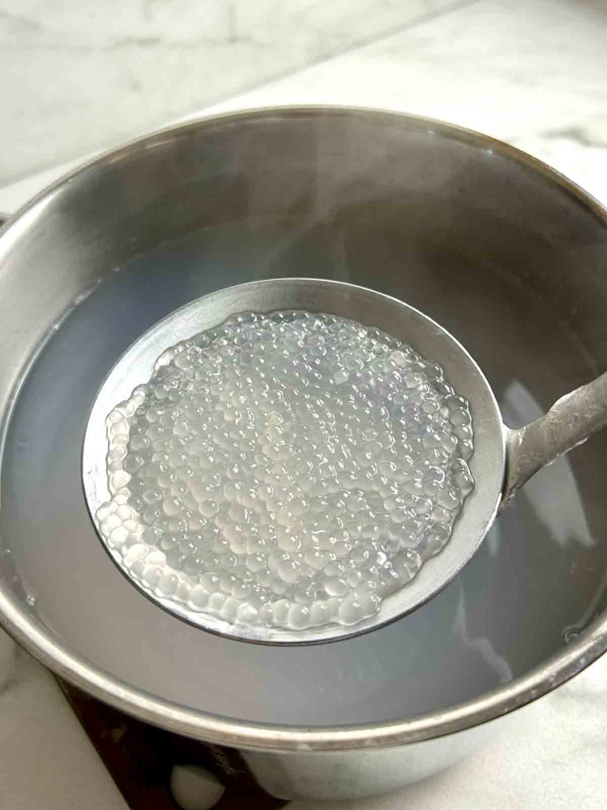 lifting cooked tapioca pearls from boiling water.