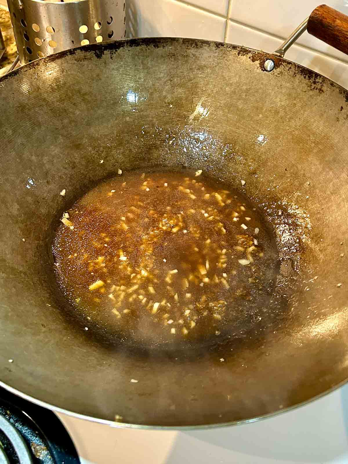 sauce mixture being thickened in wok.