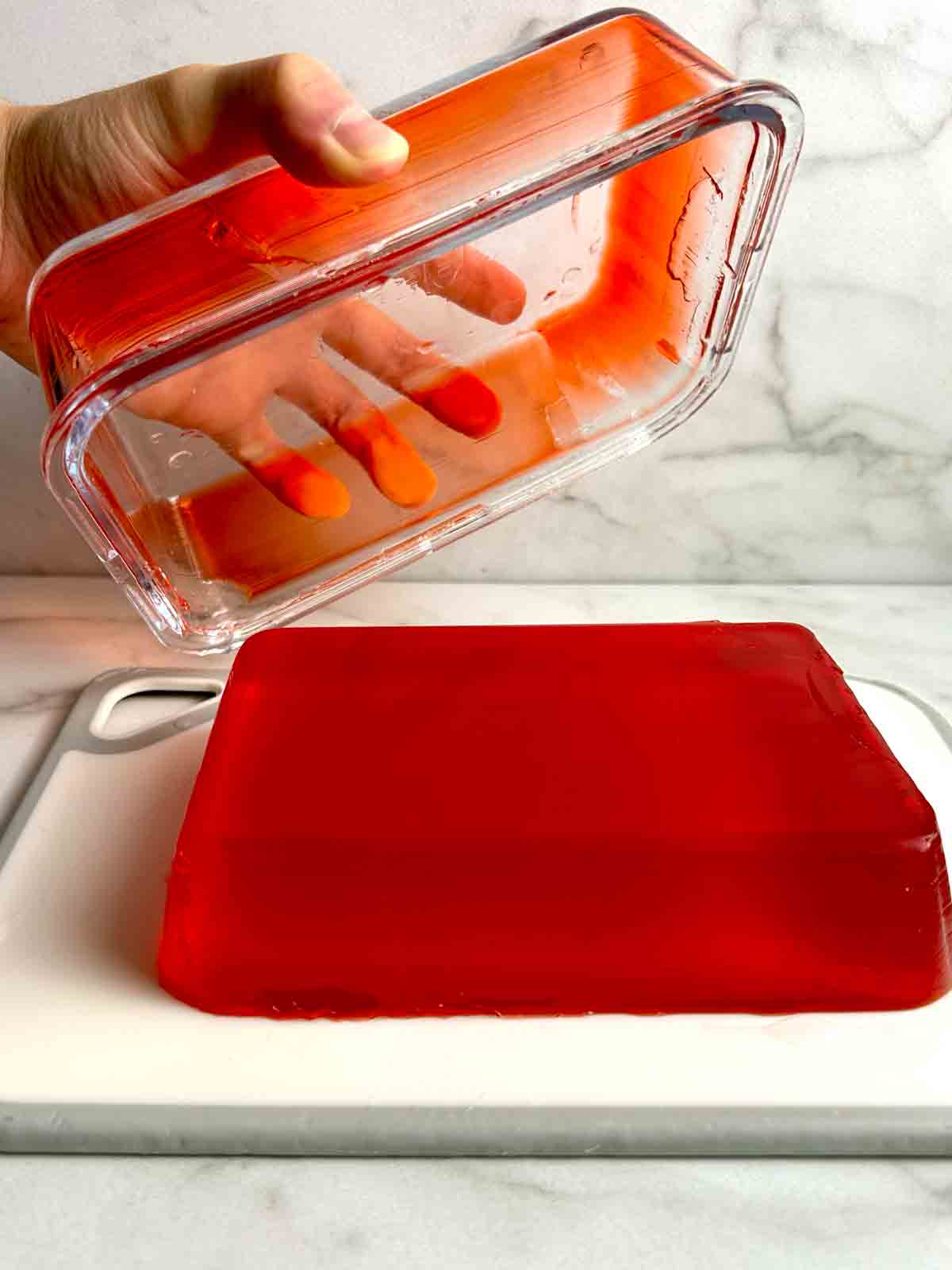 container being lifted off slab of jello.