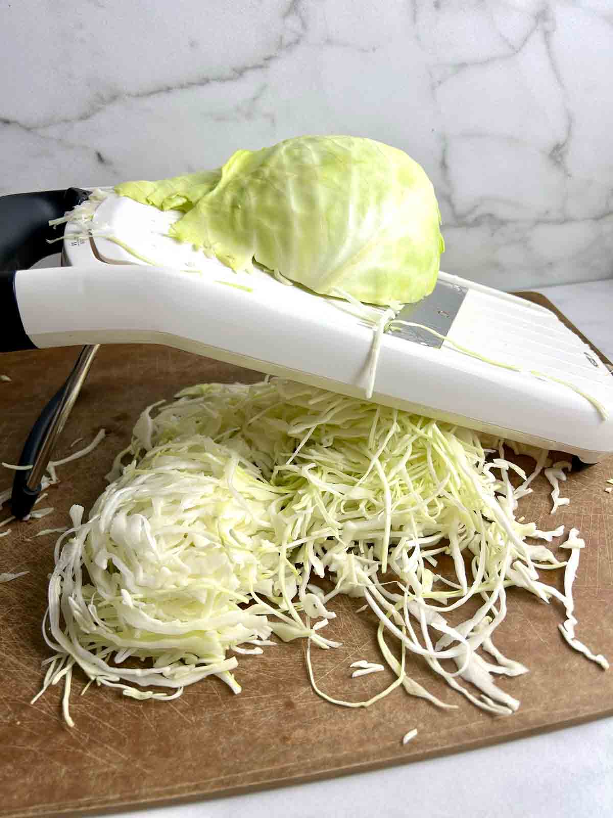 cabbage being thinly sliced on mandolin.