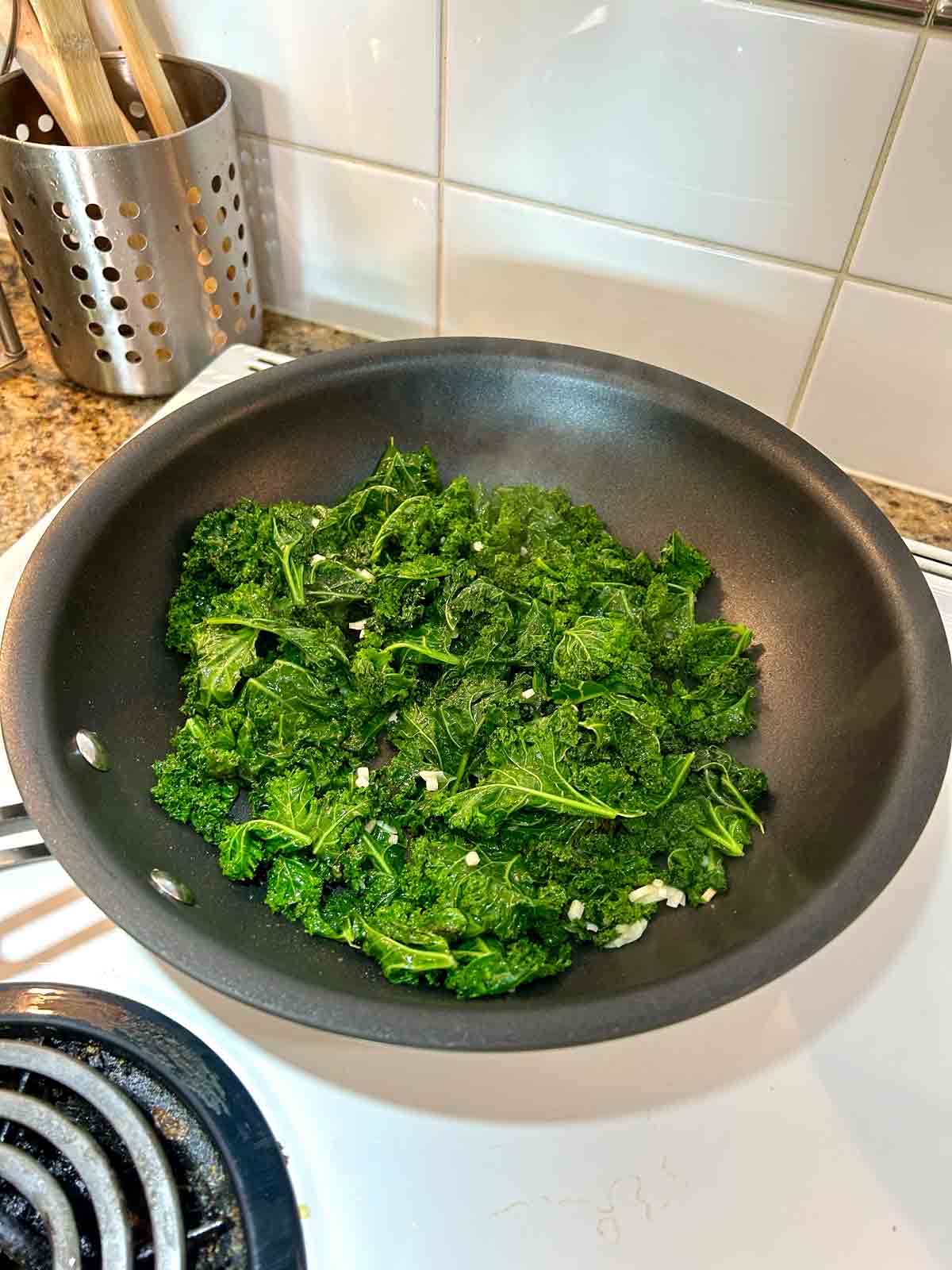 sauce being mixed with kale.