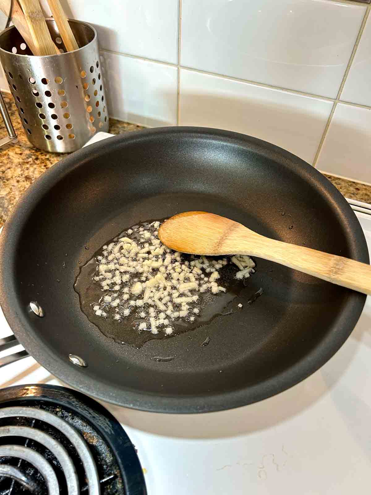 chopped garlic being cooked in oil in pan.