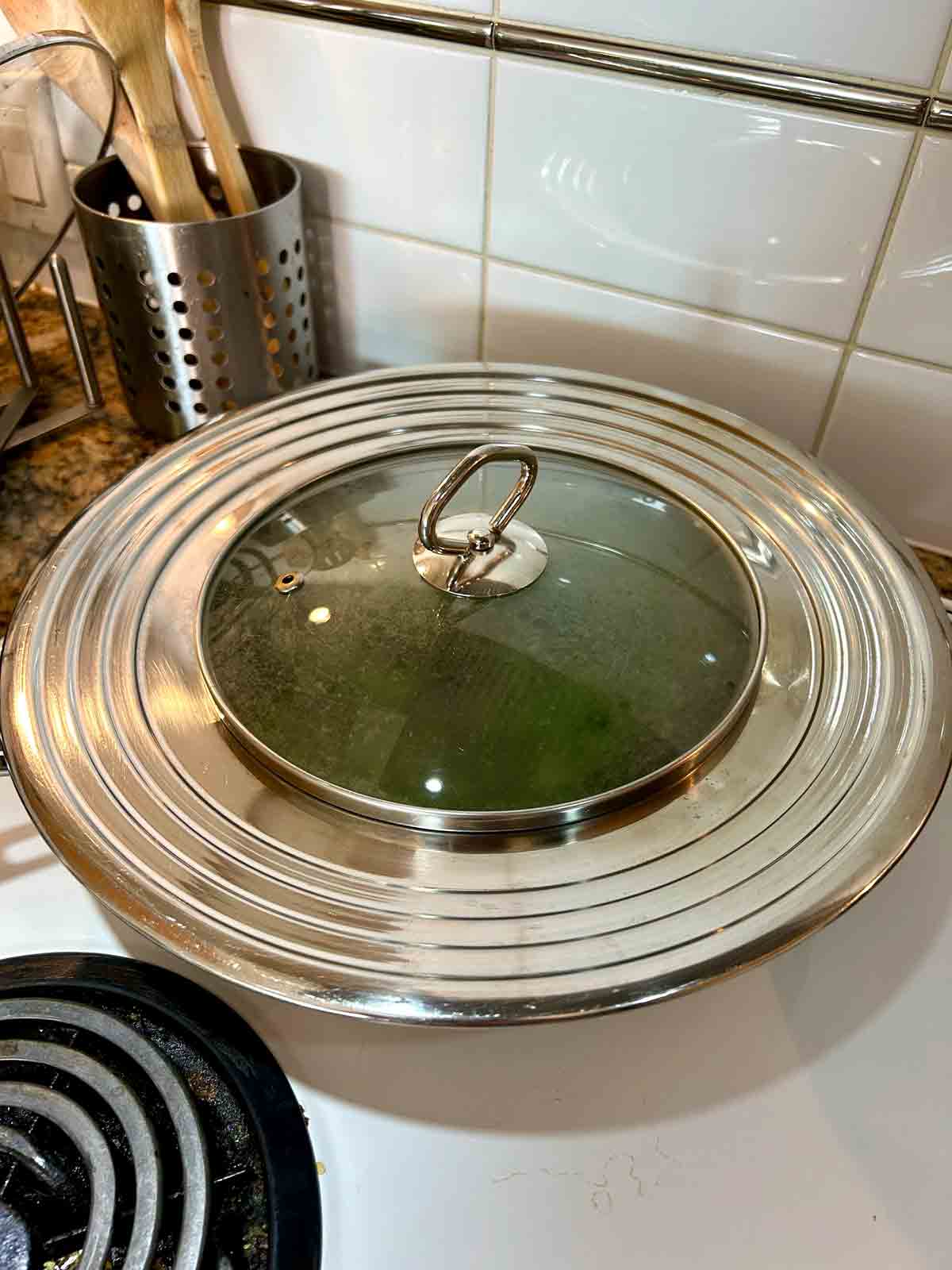 steaming lid placed over pan of kale.