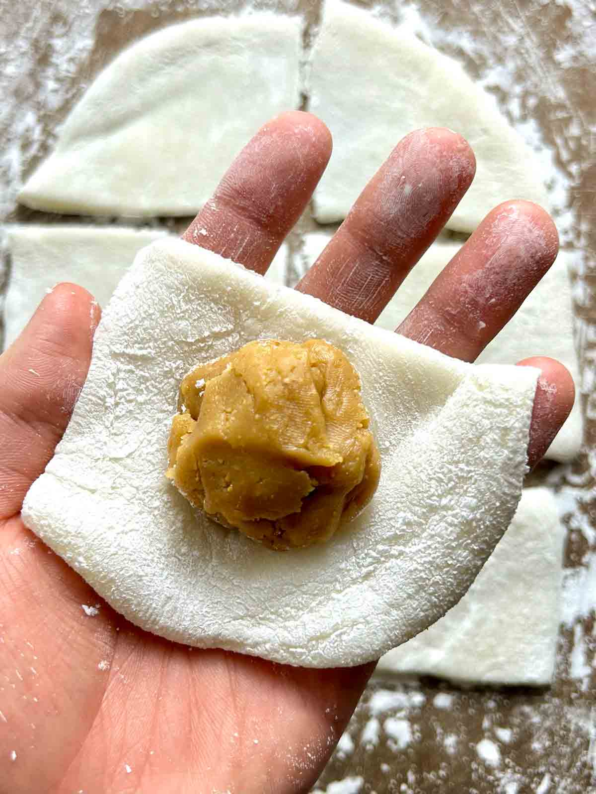 scoop of peanut butter filling on top of piece of mochi dough.