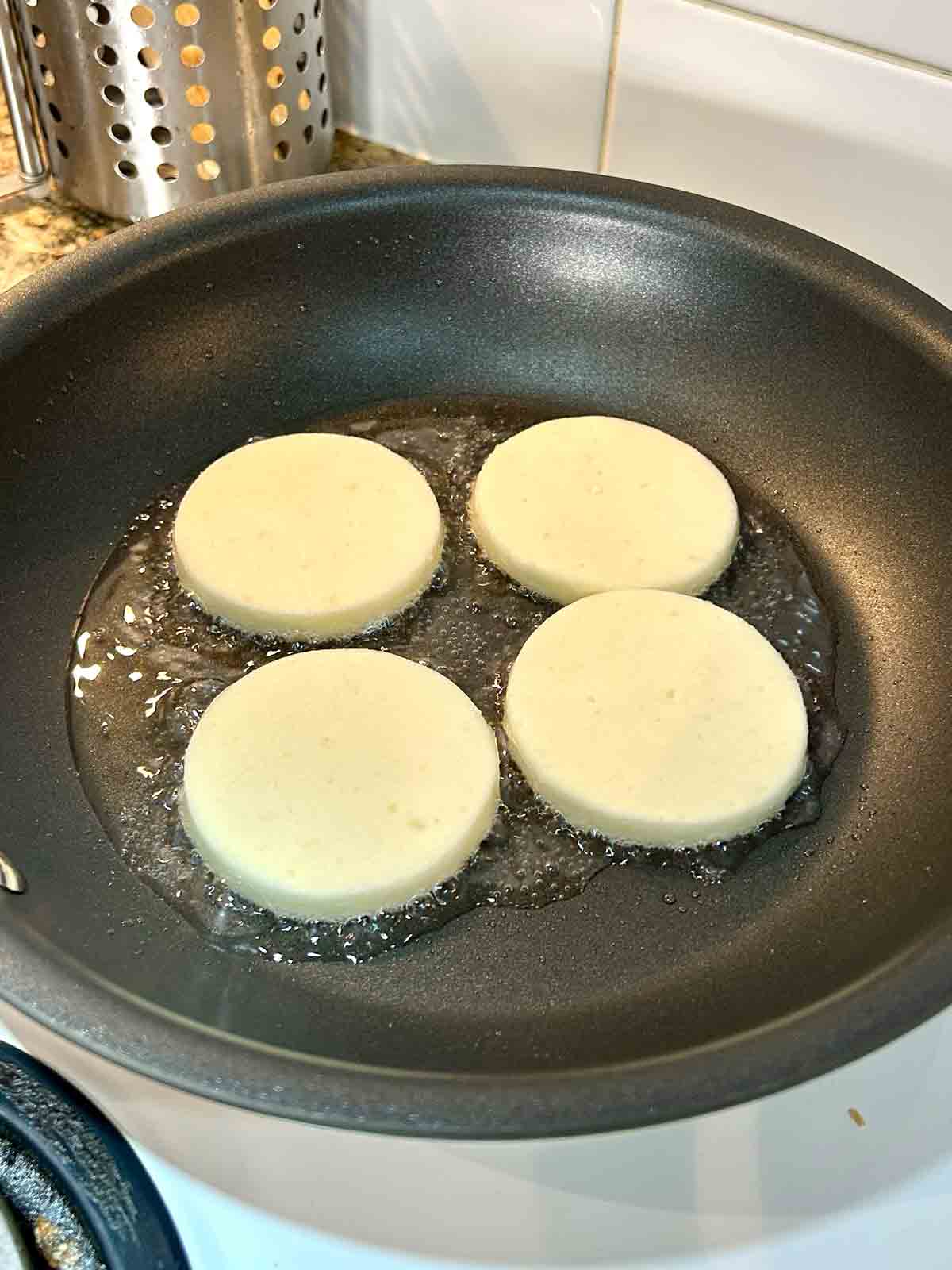 first side of potato mochis being cooked in pan.