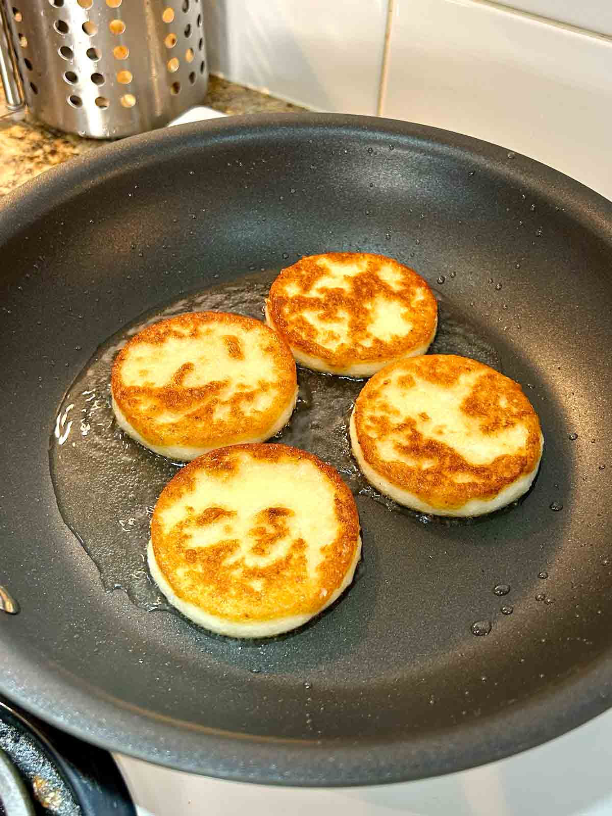 second side of potato mochis being cooked in pan.