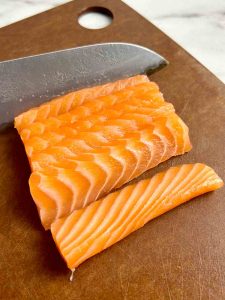 slicing salmon fillet into slices.