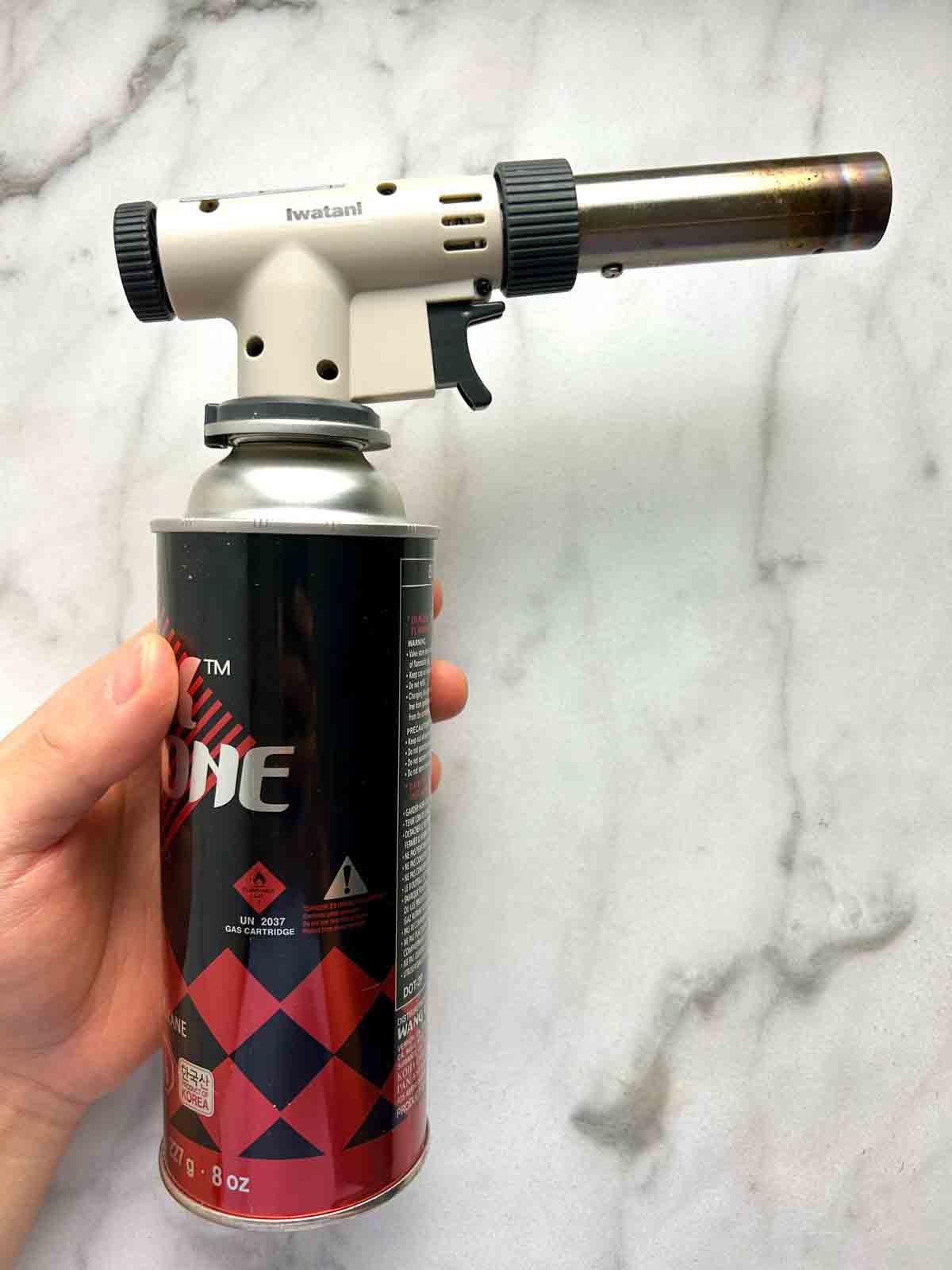 Iwatani blow torch with butane canister attached.