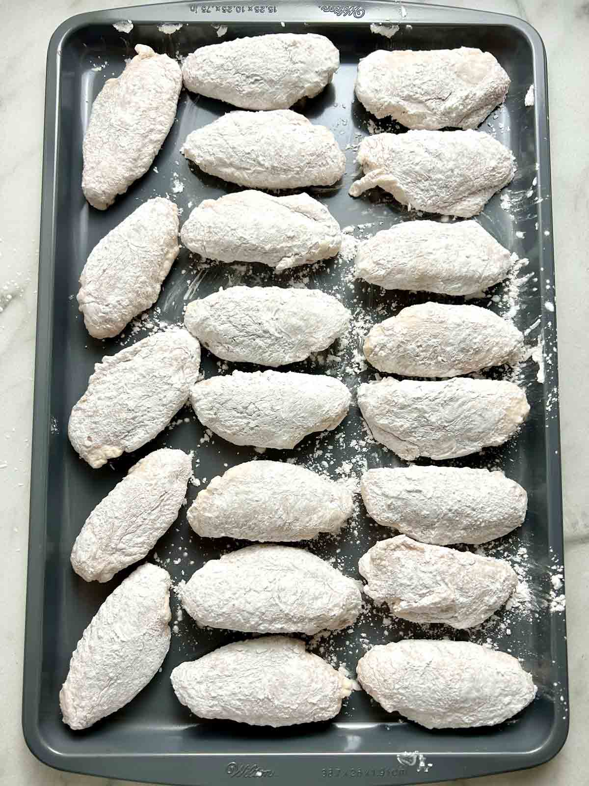 dredged chicken wings resting on baking sheet.