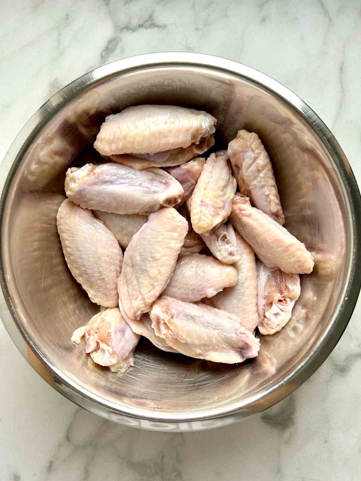 chicken wings being mixed with wet ingredients.