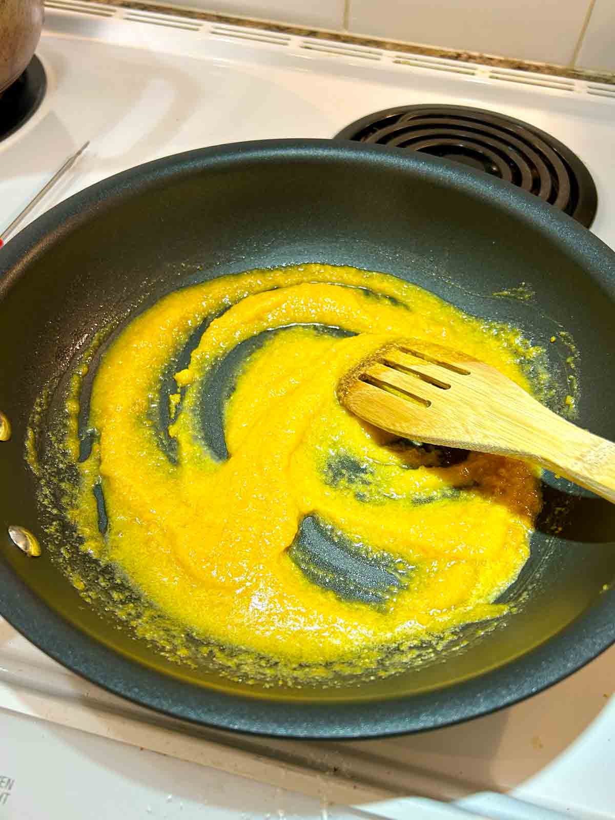 salted egg yolk sauce being cooked in large nonstick pan.