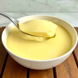 spoon lifting a chunk of steamed egg pudding out of a bowl.