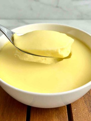 spoon lifting a chunk of steamed egg pudding out of a bowl.