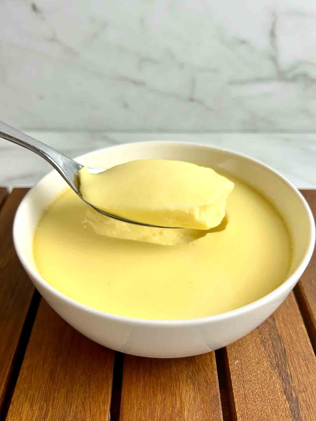 spoon lifting a chunk of steamed egg pudding out of a bowl.